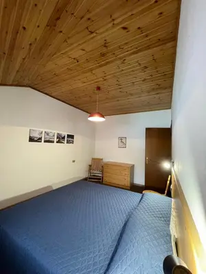 a bedroom with a blue bed and a wooden ceiling at Simi Dolomiti in Predazzo