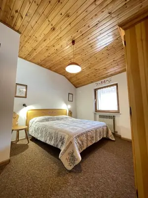 a bedroom with a large bed with a wooden ceiling at Simi Dolomiti in Predazzo