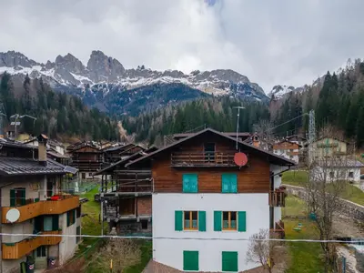 a white building with a tree in front of it at Casa Col di Frena in Falcade