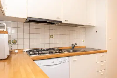 a kitchen with white cabinets and a sink and a stove at Alpe Verde in Falcade