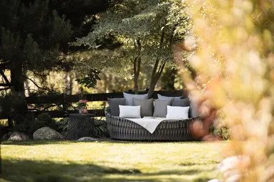 a couch sitting in the grass in a yard at DER MESNERWIRT - 4 Superior - Meraner Land in Avelengo