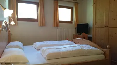 two beds in a bedroom with two windows at Hotel Jú Furcia in San Vigilio Di Marebbe