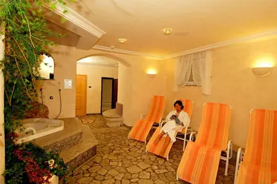 a woman sitting in an orange chair in a bathroom at Hotel Jú Furcia in San Vigilio Di Marebbe