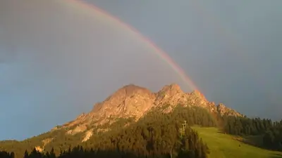 a rainbow in front of a mountain at Hotel Jú Furcia in San Vigilio Di Marebbe