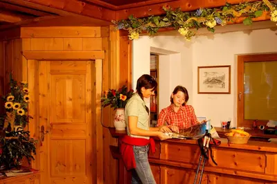 two women standing in a kitchen with a laptop at Hotel Jú Furcia in San Vigilio Di Marebbe