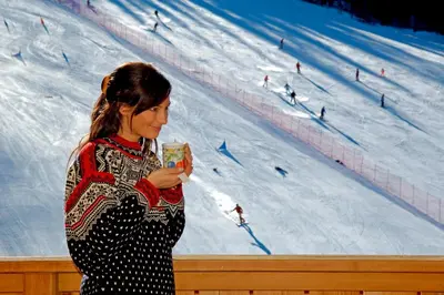 a woman standing in front of a ski slope at Hotel Jú Furcia in San Vigilio Di Marebbe
