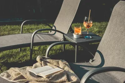 a table with a book and a glass of wine at Hotel Turmwies in Tirolo