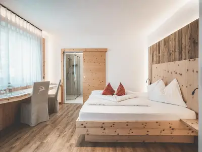 a bedroom with a large bed and a wooden headboard at Hotel Turmwies in Tirolo