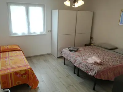 a bedroom with a bed and a cabinet and two windows at Villa in Val di Fiemme in Cavalese
