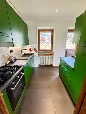a kitchen with green cabinets and a stove at Charme alpino e modernità-Appartamento ristrutturato a due passi dal centro in Cortina dʼAmpezzo