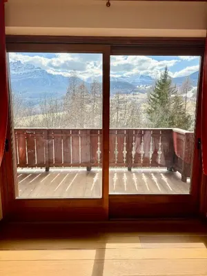 a window with a view of a balcony with mountains at Charme alpino e modernità-Appartamento ristrutturato a due passi dal centro in Cortina dʼAmpezzo