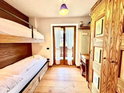 a bedroom with two bunk beds and a desk at Charme alpino e modernità-Appartamento ristrutturato a due passi dal centro in Cortina dʼAmpezzo