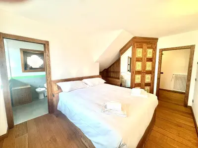 a bedroom with a large white bed in a room at Charme alpino e modernità-Appartamento ristrutturato a due passi dal centro in Cortina dʼAmpezzo