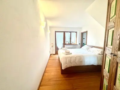 a bedroom with a white bed and a wooden floor at Charme alpino e modernità-Appartamento ristrutturato a due passi dal centro in Cortina dʼAmpezzo