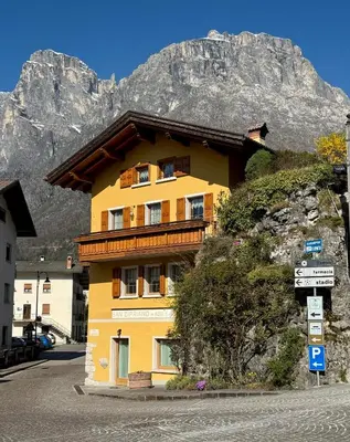 a yellow building with a mountain in the background at Apartment Enrosadira in Taibon