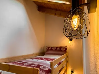 a small room with a bed and a chandelier at Apartment Penia 2-3 by Interhome in Canazei