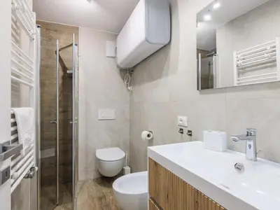 a white bathroom with a sink and a mirror at Apartment Penia 2-3 by Interhome in Canazei