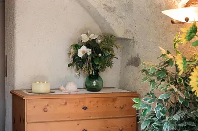 a vase with flowers on top of a dresser with a candle at Ansitz Wendelstein in Appiano sulla Strada del Vino