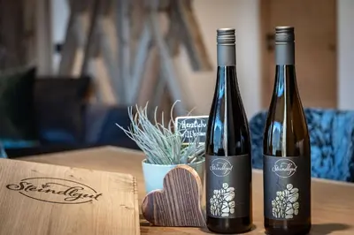 two bottles of wine sitting on a wooden table at Steindlgut - Weinberg Chalets in Brixen