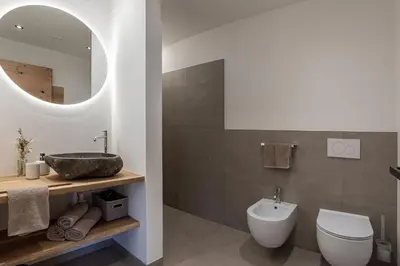 a bathroom with a sink and a toilet and a mirror at Steindlgut - Weinberg Chalets in Brixen