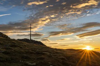 a cross on top of a hill at sunset at Schienhof in Chiusa