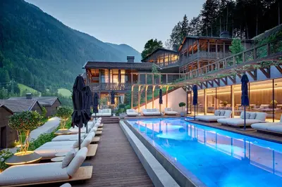 a hotel with a swimming pool with lounge chairs at AMONTI Chalets in Molini di Tures