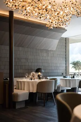 a dining room with tables and chairs and a chandelier at AMONTI Chalets in Molini di Tures