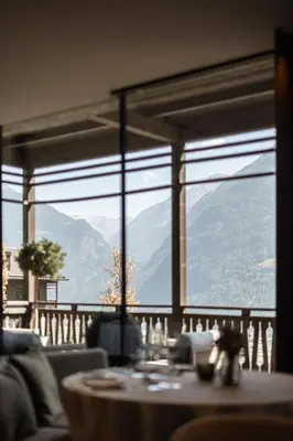 a room with a table with a view of mountains at AMONTI Chalets in Molini di Tures