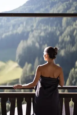 a woman sitting on a balcony looking out of a window at AMONTI Chalets in Molini di Tures