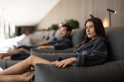a woman sitting on a couch with a man at AMONTI Chalets in Molini di Tures