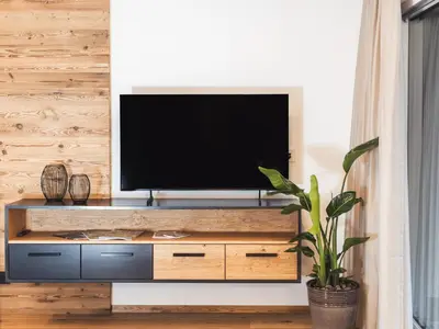 a television on a wooden entertainment center in a living room at Paradeis Apartments in Mühlbach