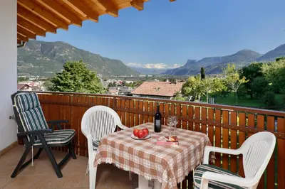 a table and chairs on a balcony with a bottle of wine at Kircherhof in Marlengo