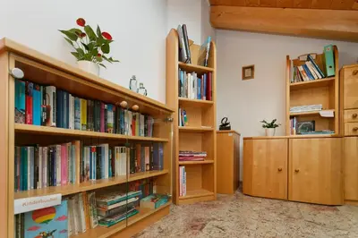 a library with wooden shelves filled with books at Kircherhof in Marlengo