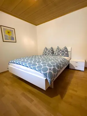 a bedroom with a bed with a blue comforter at Apartment Rosengarten - Rosenheim Apartments in Tires