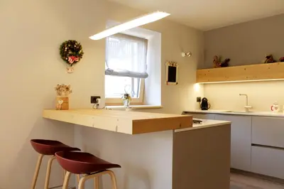 a kitchen and living room with a counter and stools at VILLA CAVAZZAL - 2 camere, 2 bagni, garage Dolomiti Affitti in Cavalese