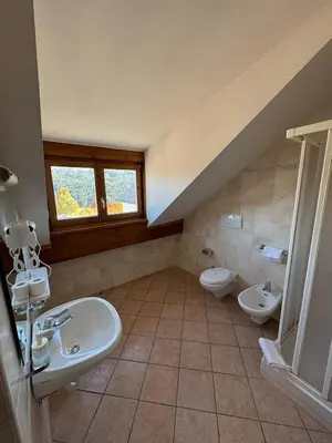 a bathroom with two toilets and a sink and a window at Hotel Pietralba in Madonna di Petralba