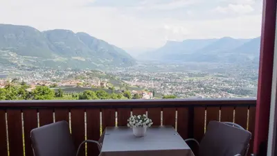 a table and chairs on a balcony with a view at Garni Praidlerhof in Tirolo