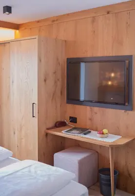 a room with a table with a tv on a wall at Garni Praidlerhof in Tirolo