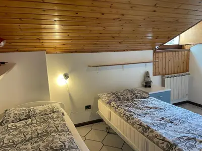 a bedroom with two beds and a wooden ceiling at Casa Leo By Gonewlocation in Cavalese