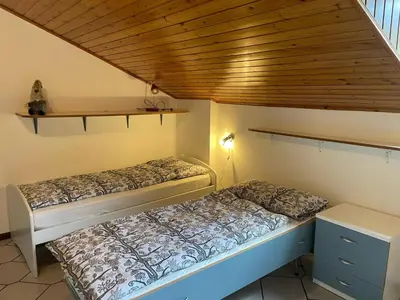 two beds in a small room with a wooden ceiling at Casa Leo By Gonewlocation in Cavalese
