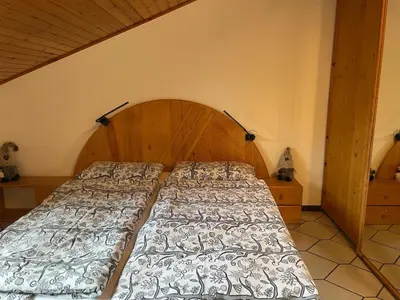 a bedroom with a large bed with a wooden headboard at Casa Leo By Gonewlocation in Cavalese