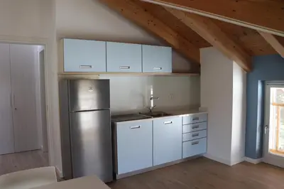 a kitchen with a stainless steel refrigerator and white cabinets at Casa Dusinei Blue & Green in Cles