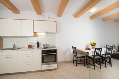 a kitchen with white cabinets and a table with chairs at Vintler Apartments in Bolzano
