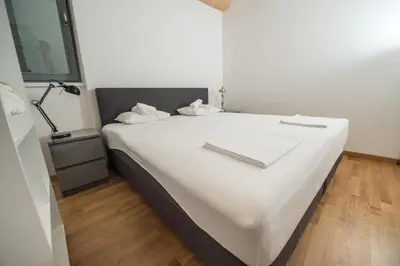a white bed in a room with a lamp at Vintler Apartments in Bolzano