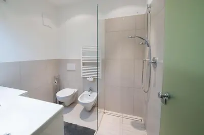 a bathroom with a toilet and a glass shower stall at Vintler Apartments in Bolzano