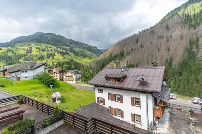 a building in a village with mountains in the background at Col da Daut 8 in Rocca Pietore