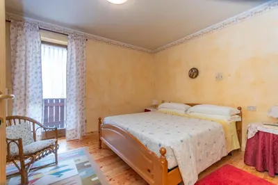 a bedroom with a bed and a chair and a window at Col da Daut 8 in Rocca Pietore