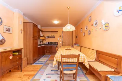 a kitchen with a table and chairs in a room at Col da Daut 8 in Rocca Pietore