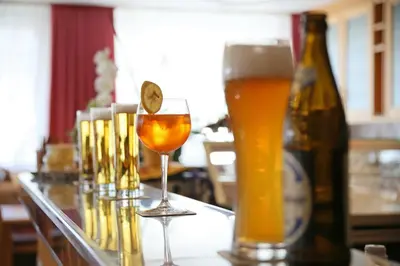 a table with glasses of beer and a bottle at Pension Alpenhof B&B in Colle Isarco