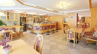 a restaurant with tables and chairs and a bar at Pension Alpenhof B&B in Colle Isarco